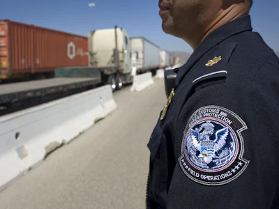 A U.S. Customs and Border Protection (CBP) officer stands next to a line of trucks entering from Mexico at the Otay Mesa Cargo Port of Entry in San Diego, California. Photo: Bloomberg.