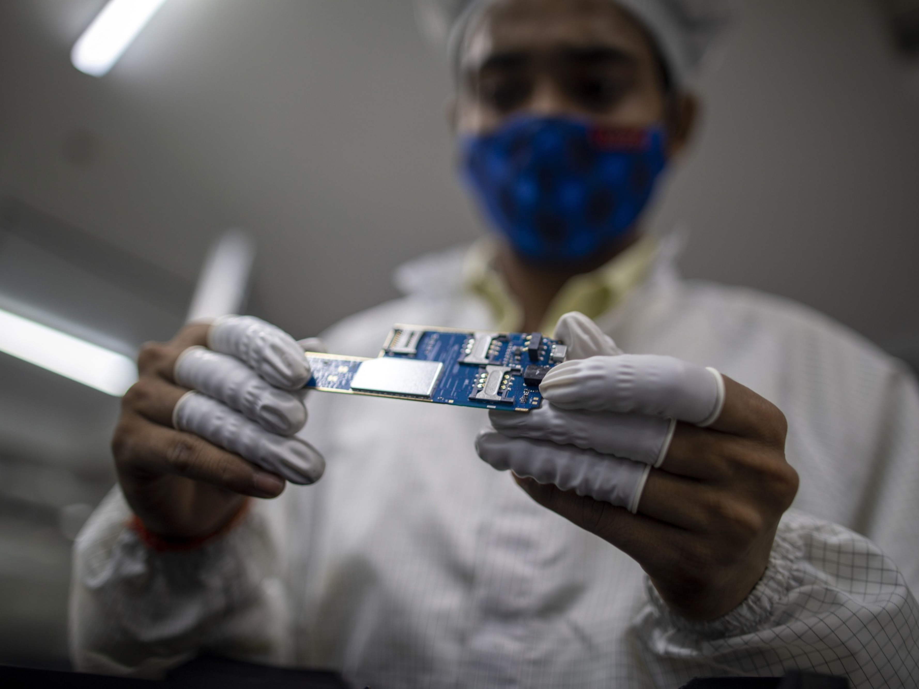 An electronics factory employee handles a circuit board. Photo: Bloomberg.