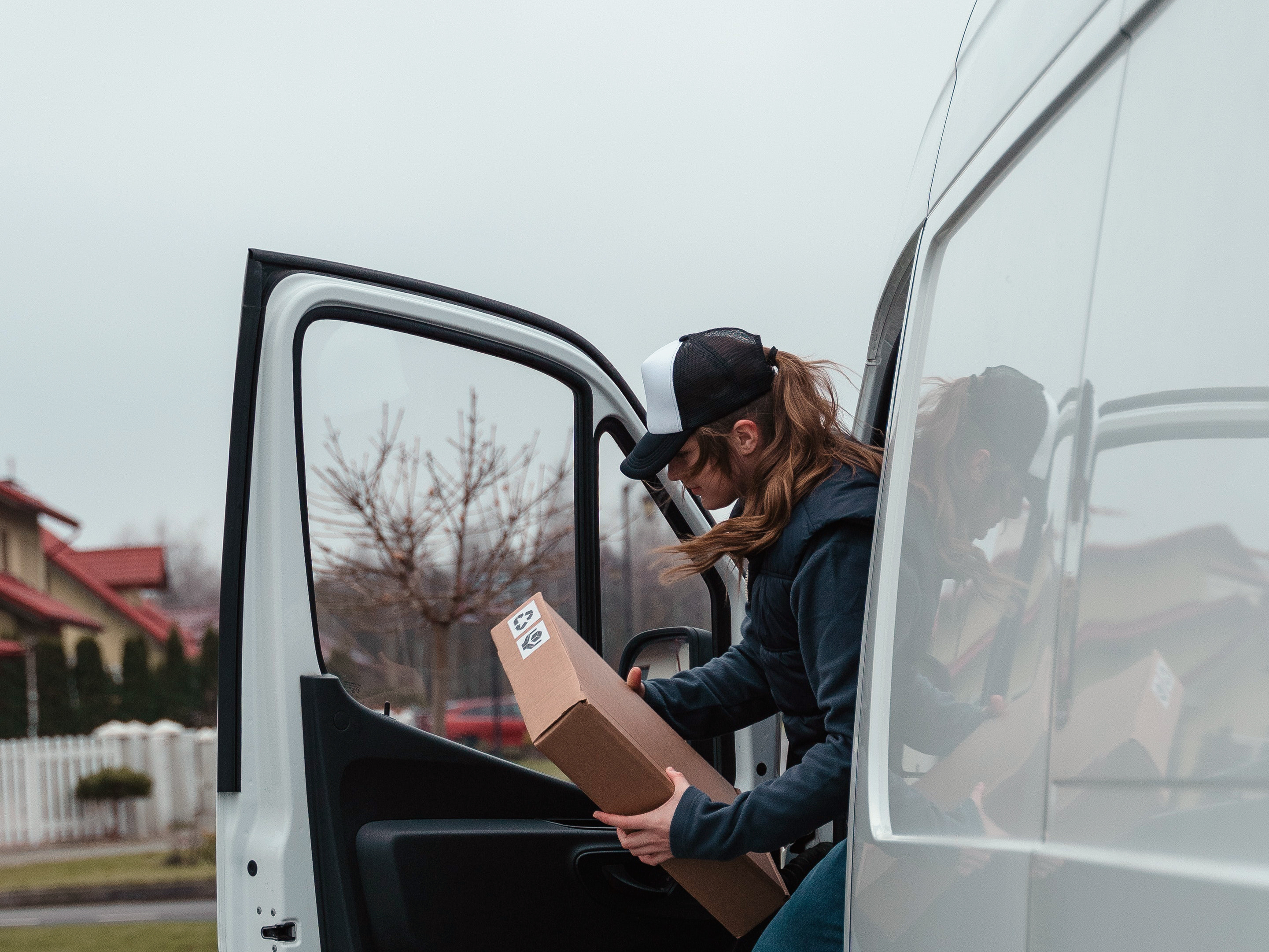 A delivery driver holding a package exits her van. Photo: Pexels.