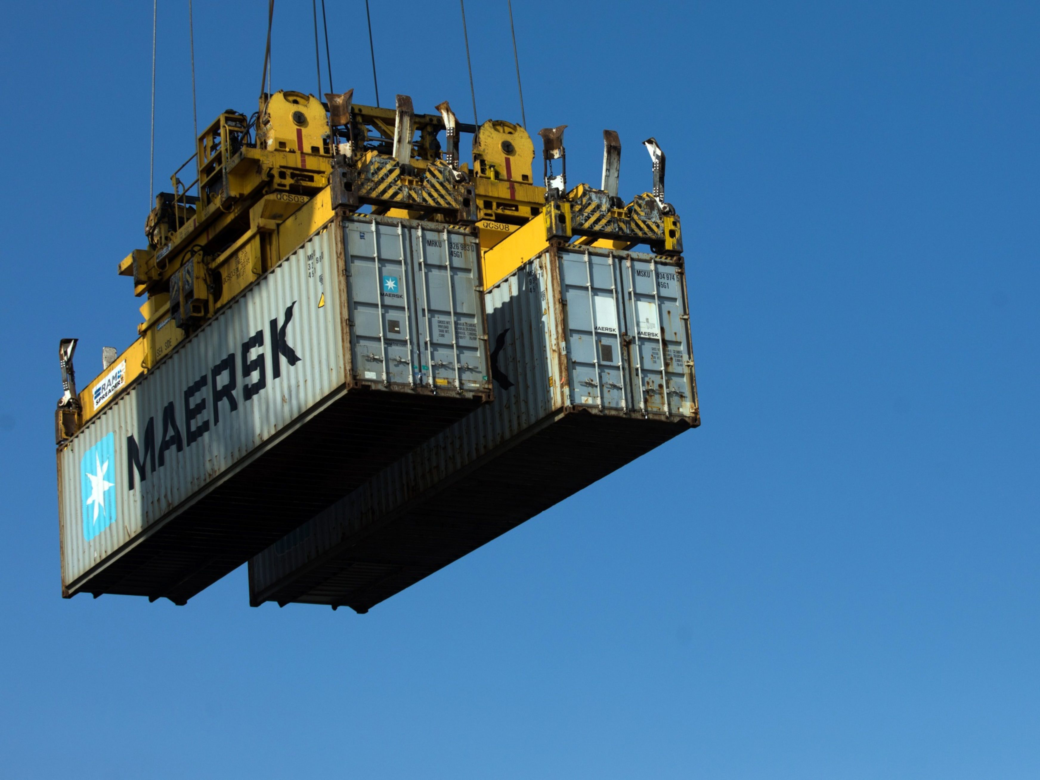 A crane carries shipping containers owned by AP Moller-Maersk A/S away from a ship. Photo: Bloomberg.