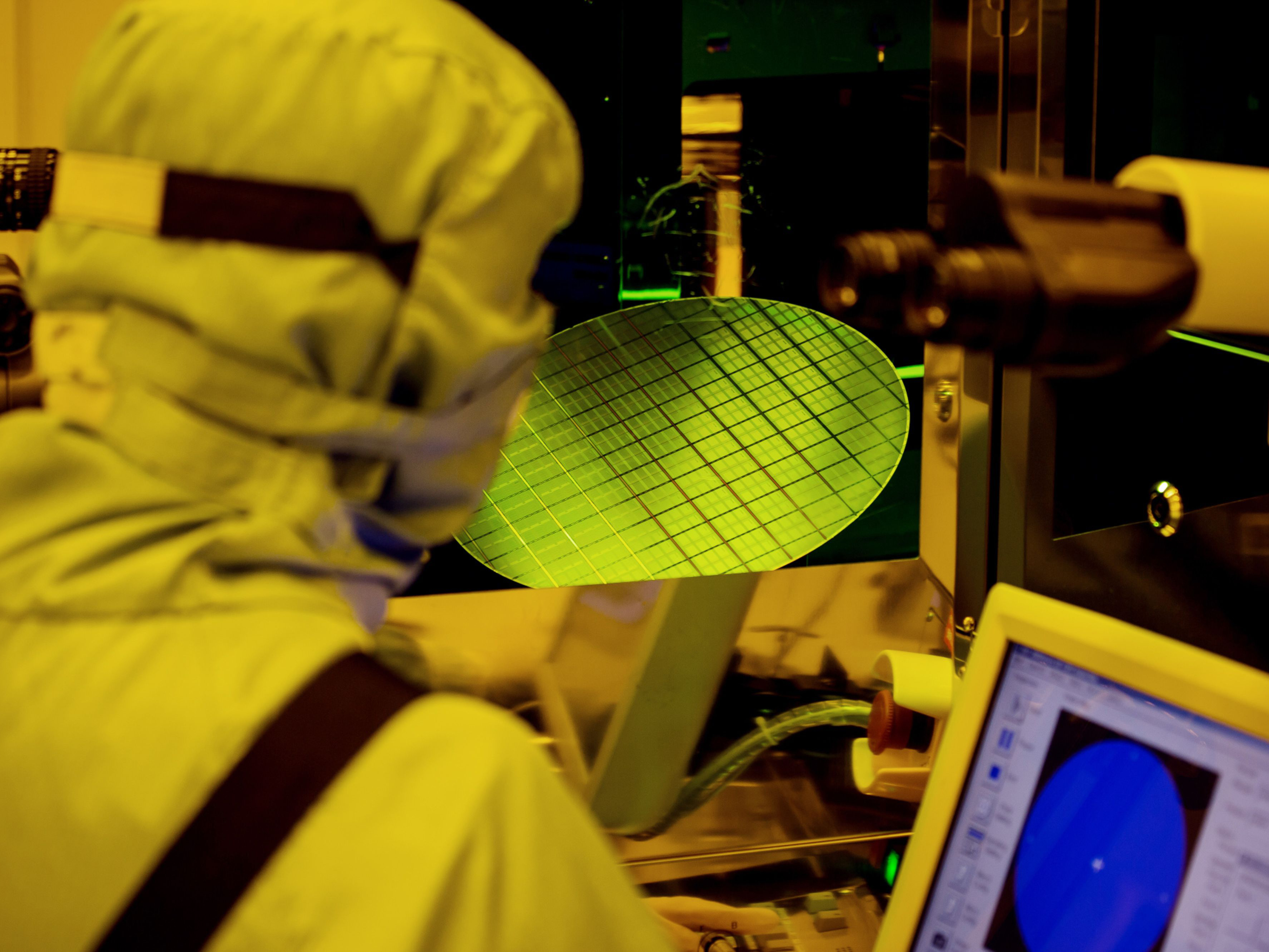 An employee inspect wafers using an optical microscope. Photo: Bloomberg.