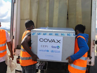 Workers unload boxes of COVAX COVID-19 vaccines in Madagascar. Photographer: Mamyrael/AFP.