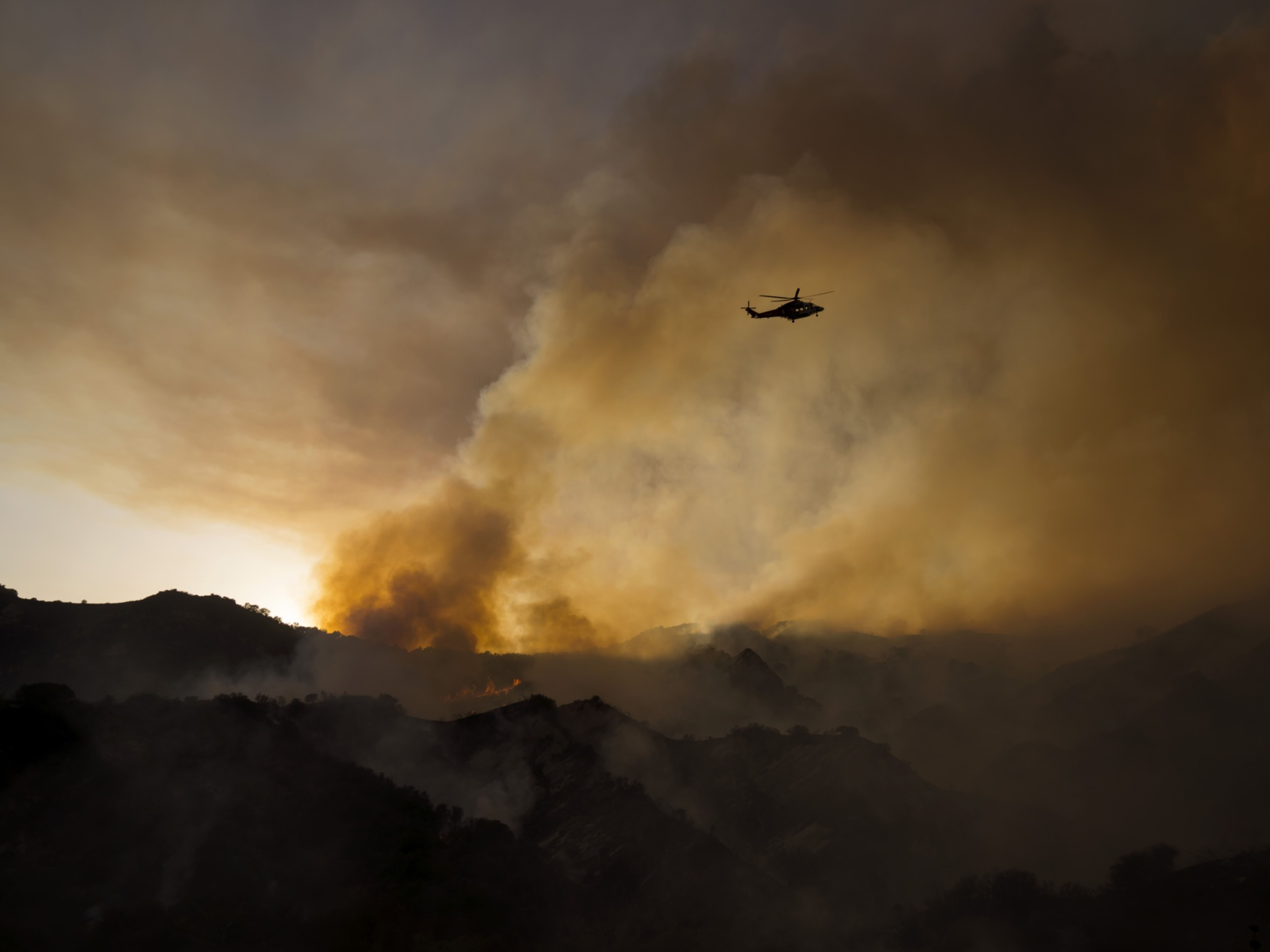A helicopter drops water on a brush fire in California. Photo: Bloomberg.