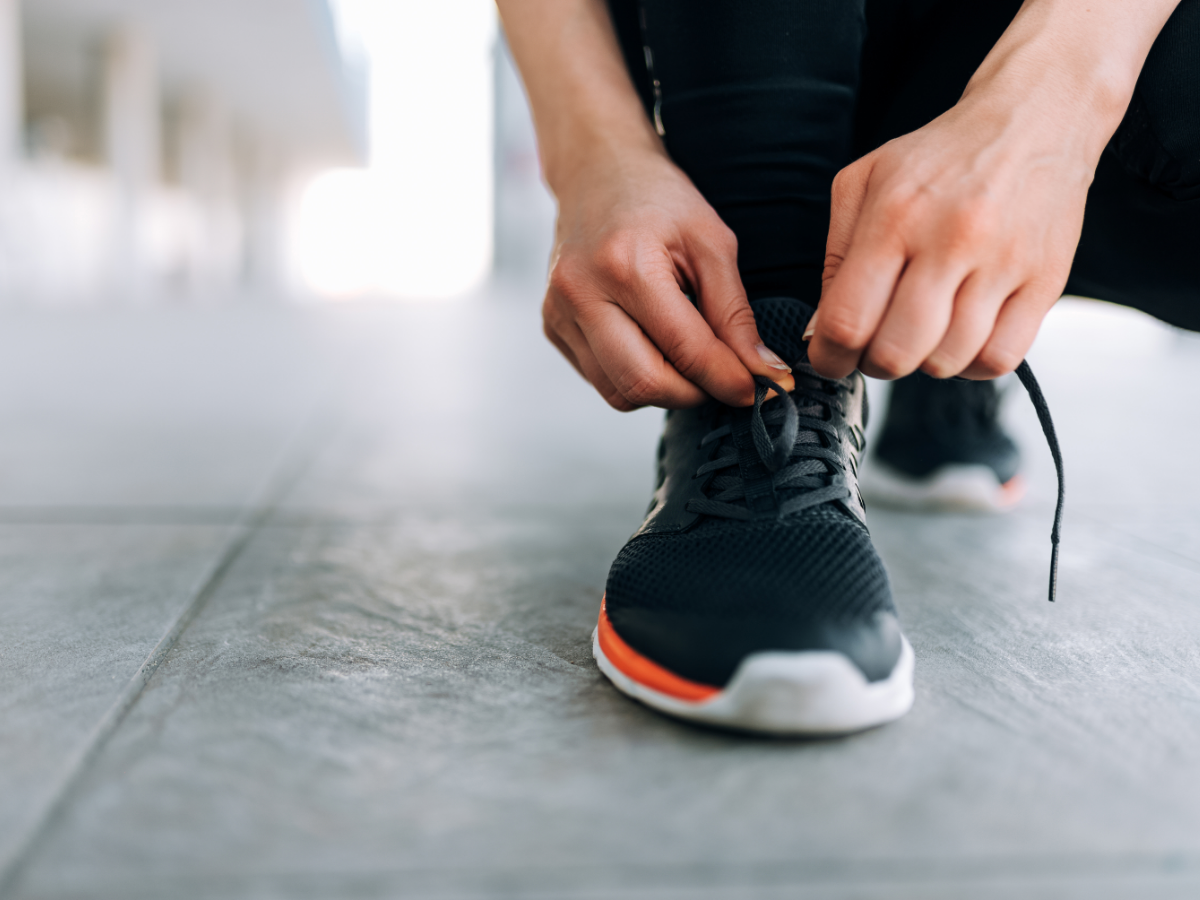 A runner stops to tie their shoelace. Photo: Canva.