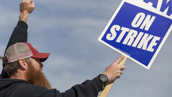 A Deere & Co. worker holds a sign during a strike outside the John Deere Des Moines Works facility in Ankeny, Iowa. Photo: Bloomberg.