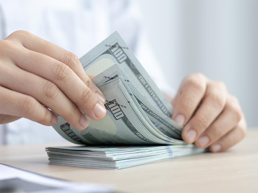 A financial manager counts U.S. $100 bills. Photo: tapanakorn/ Canva.
