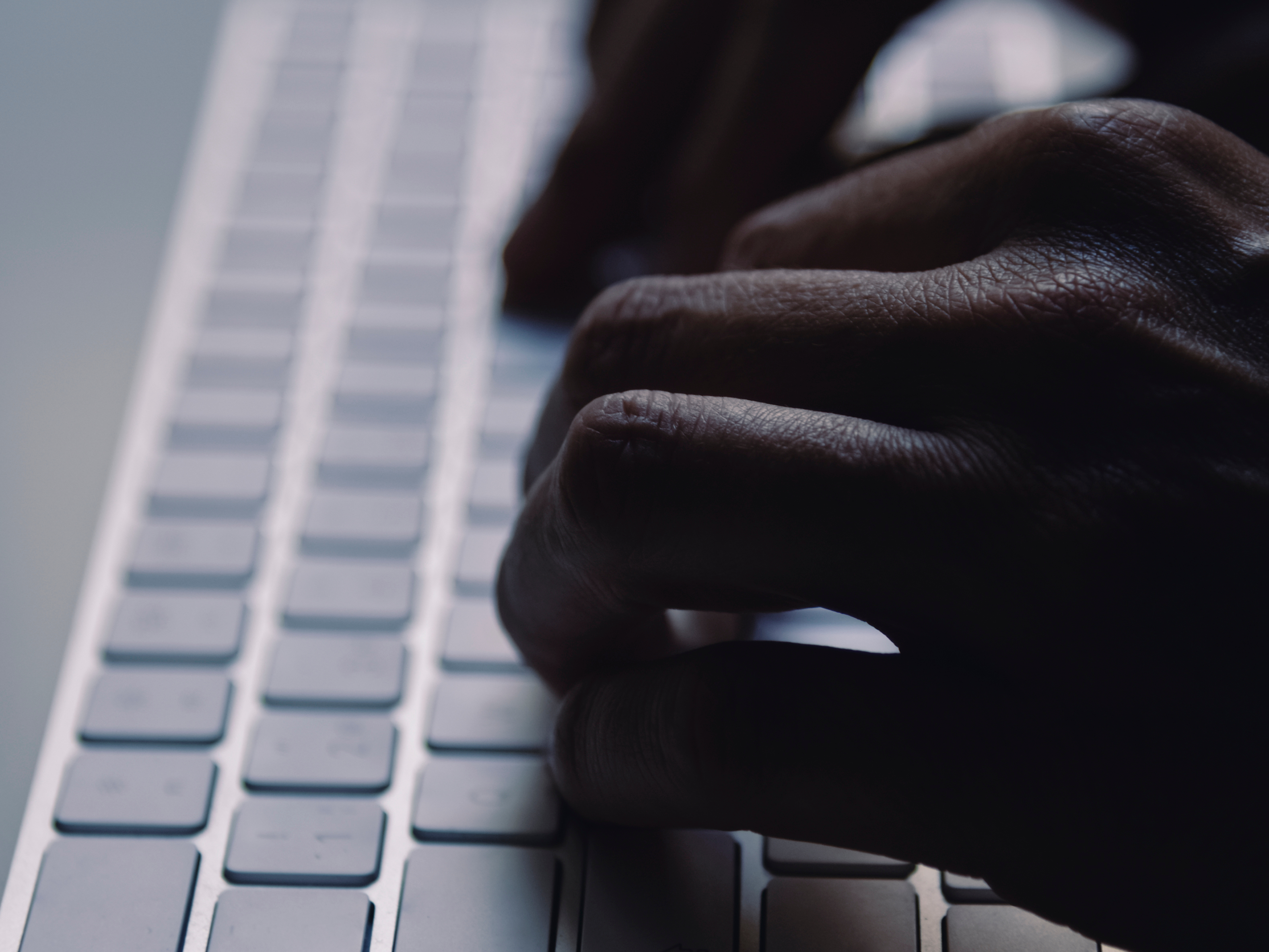 A man types on a computer keyboard. Photo: Juan Moyano/ Canva.
