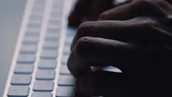 A man types on a computer keyboard. Photo: Juan Moyano/ Canva.