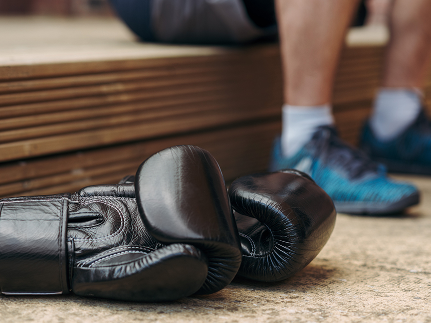 Boxing gloves rest on the floor beside their owner. Photo: Anete Lusina/ Pexels.