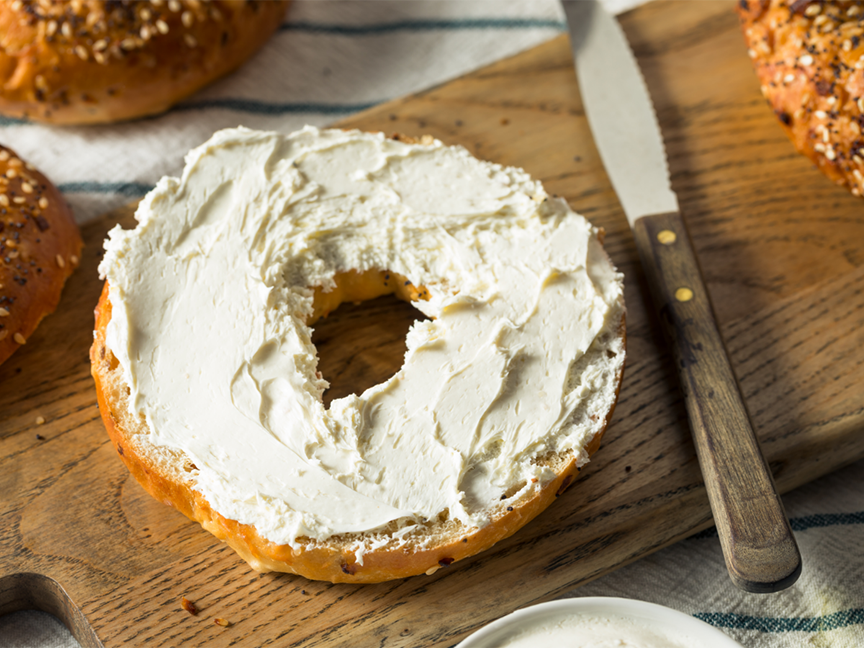 A bagel with cream cheese rests on a tray. Photo: Getty Images.