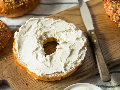 A bagel with cream cheese rests on a tray. Photo: Getty Images.