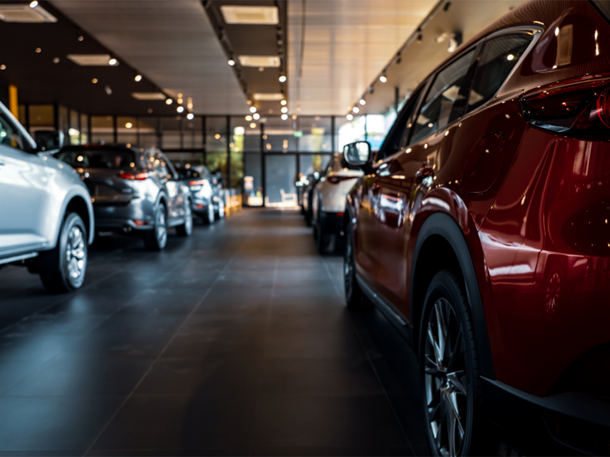 Cars are parked in a dealership showroom. Photo: Fahroni/ Canva.