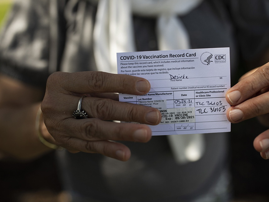 A woman holds up her vaccination card. Photo: Bloomberg.
