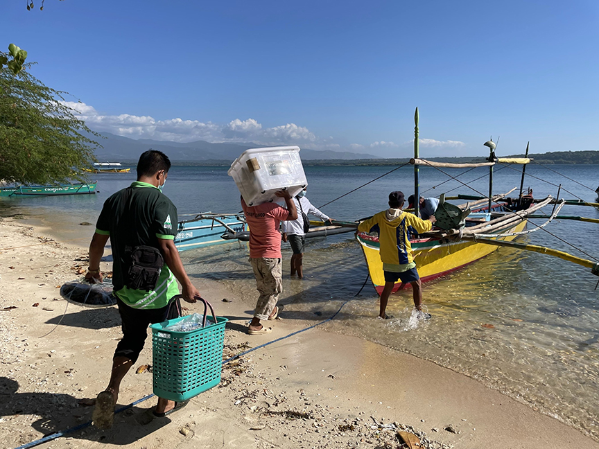Staff members load COVID-19 vaccine equipment onto a boat during a vaccine drive on the remote Philippine island of San Salvador. Photo: Bloomberg.