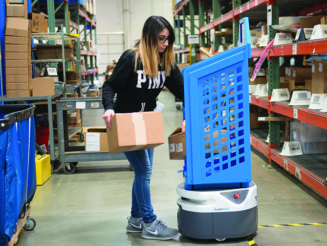 A warehouse worker puts items in a tote on an autonomous mobile robot (AMR). Photo by Lucas Systems.