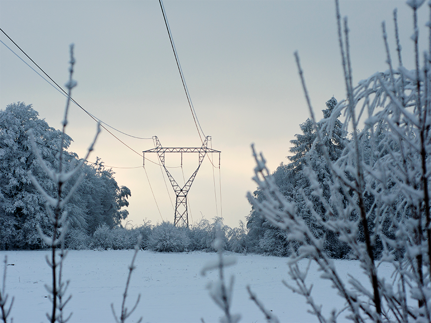 Power lines stretch over a snow-covered landscape. Photo: Getty.