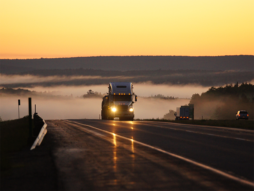 A heavy goods vehicle drives down a highway at dusk. Photo: Getty.