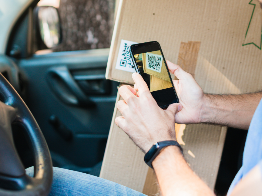 A delivery driver uses his phone to scan the QR code on a package. Photo: Getty.