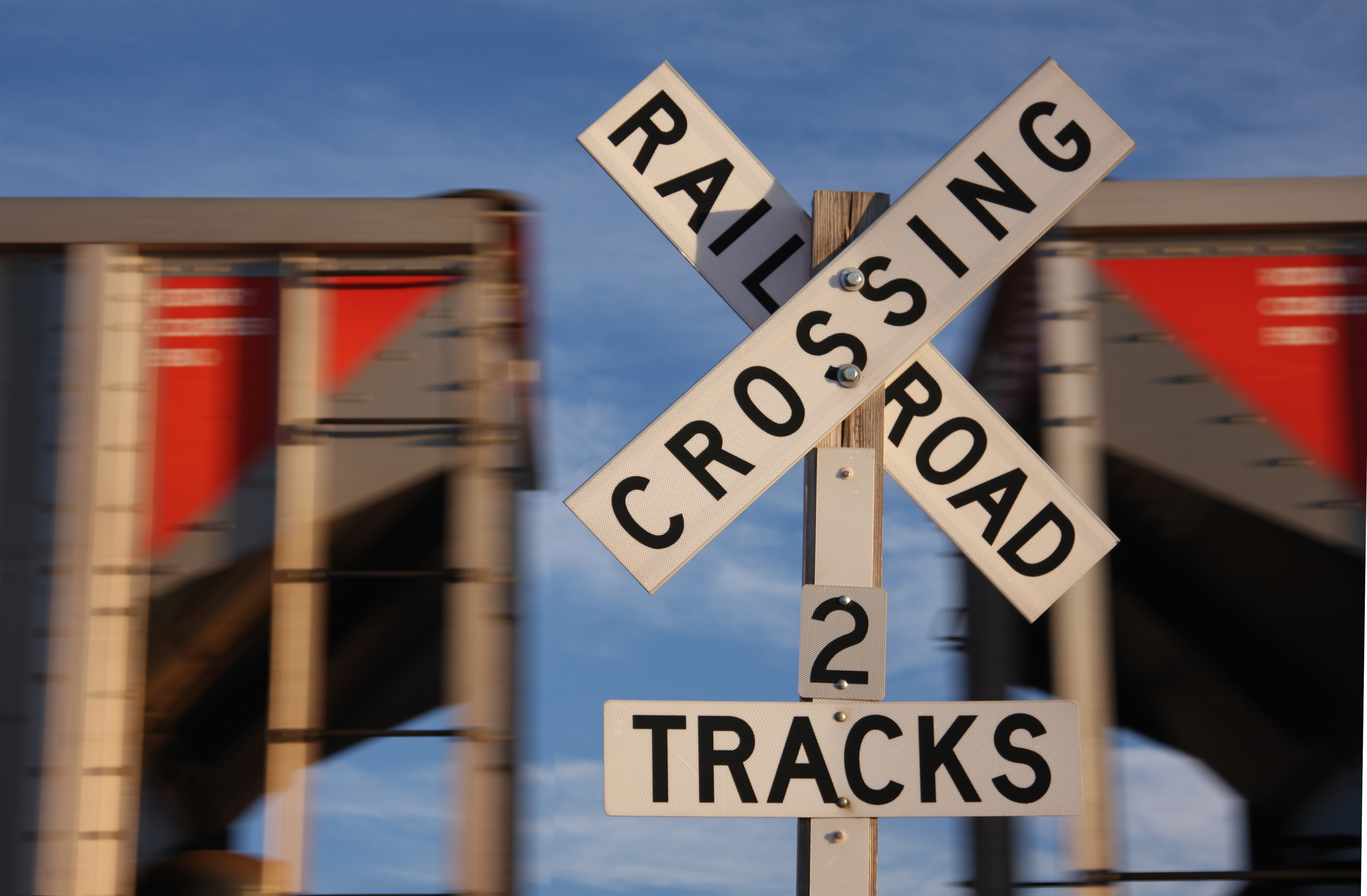A railroad crossing sign stands in front of a passing train. Photo: Getty.