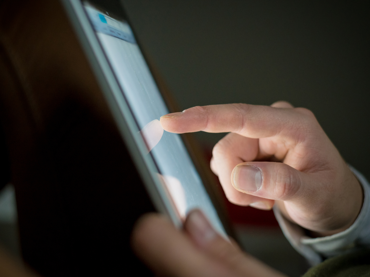 Close up of a finger touching a tablet device. Photo: Shutterstock.