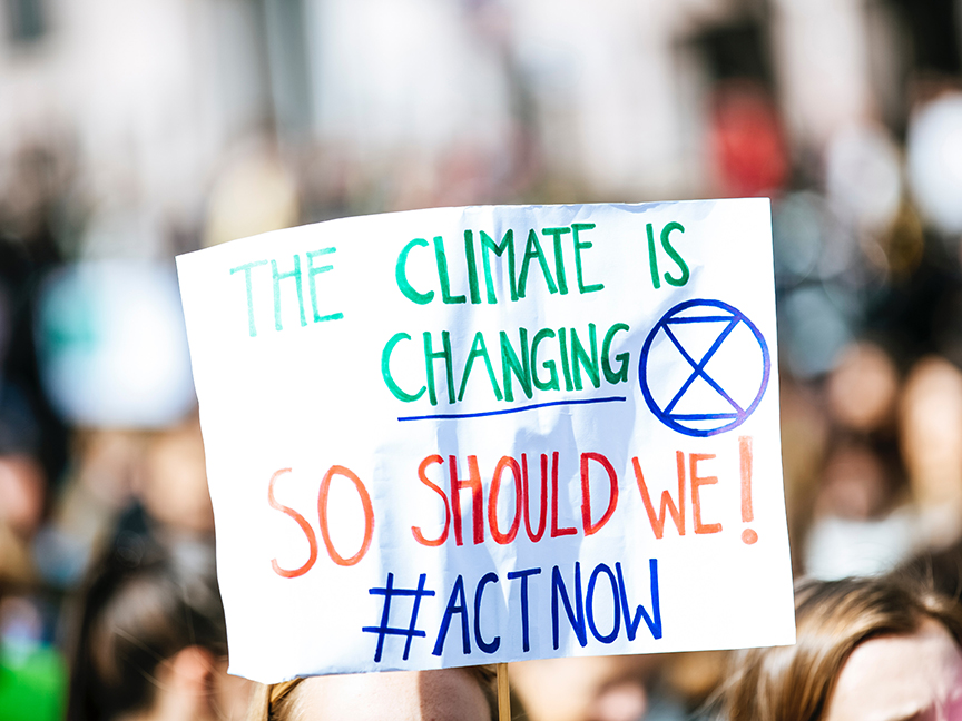 An activist carries a sign that reads, 'The climate is changing, so should we!' during the September 2019 climate strikes. Photo: Markus Spiske/ Pexels.