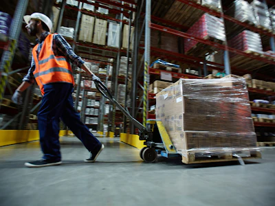 A warehouse worker uses a pallet jack to move boxes. Photo: Shutterstock.