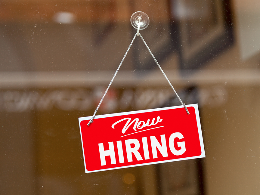 A sign reading 'Now Hiring' hangs in a window. Photo: Getty.
