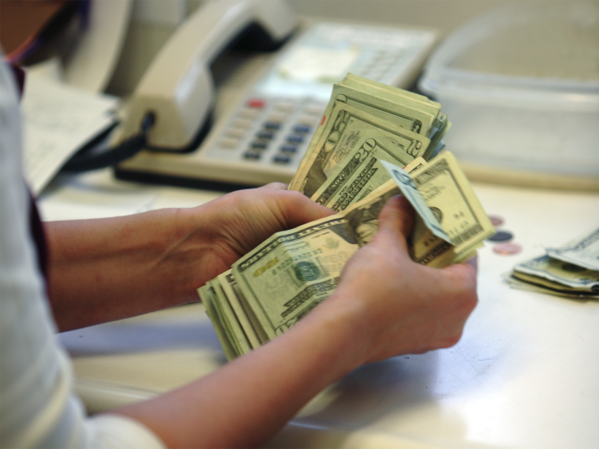 A small business manager counts cash. Photo: Getty.