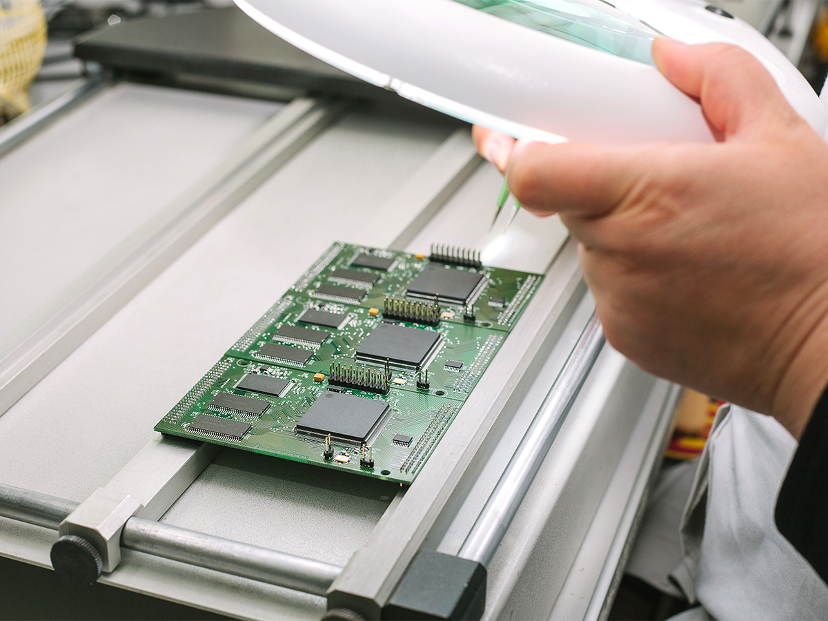 A worker inspects a circuit board at a chip manufacturing plant. Photo: Getty.