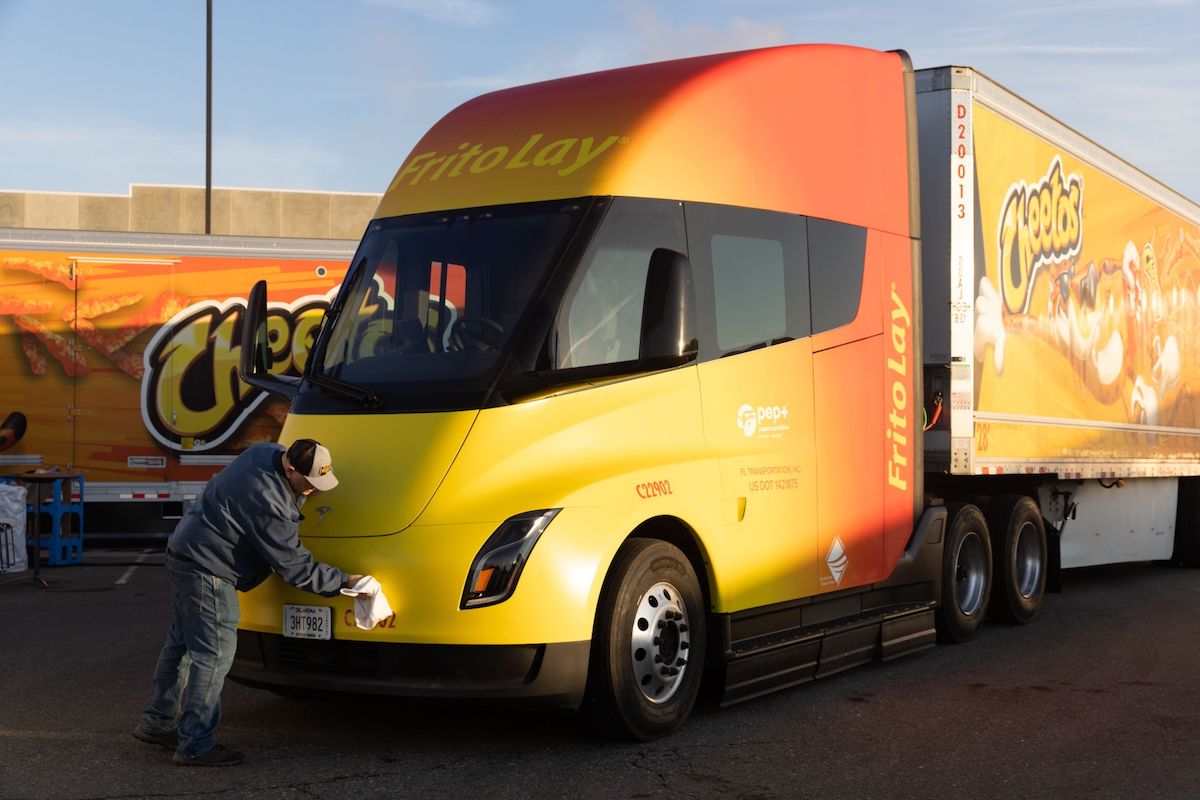 A worker cleans a Tesla Semi electric truck parked outside the Frito-Lay manufacturing facility in Modesto, California, US, on Wednesday, Jan. 18, 2023. PepsiCo...s Frito-Lay is replacing its diesel-powered freight equipment with zero-emission trucks, solar panels and energy-storage systems at it's Modesto plant. Photographer: Benjamin Fanjoy/Bloomberg