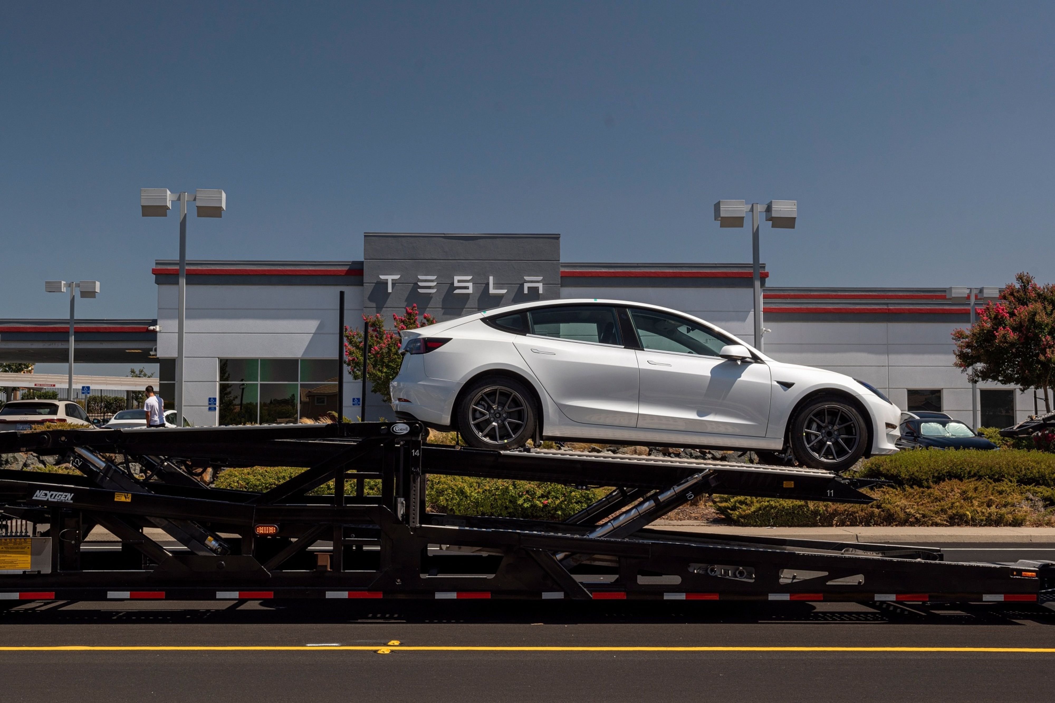 A Tesla Model 3 vehicle on an auto carrier in front of a store in Rocklin, California. Photographer: David Paul Morris/Bloomberg