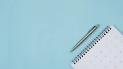 A calendar with a pen above it rests on top of a blue background. Photo: iStock.com/Rattankun Thongbun