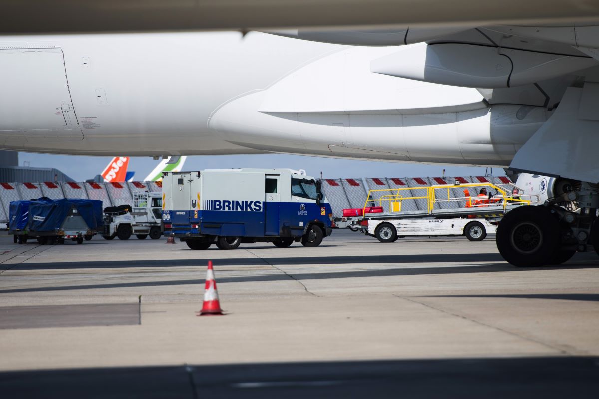 A Brinks security van beside a Boeing Co 777 passenger plane. Photographer: Nathan Laine/Bloomberg