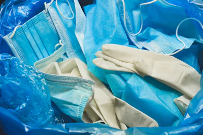 Medical trash. Coronavirus protection equipment in medical waste bin. Used face masks and sterile gloves. Doctor uniform for patient treatment in hospital. Prevention the spread of COVID-19.