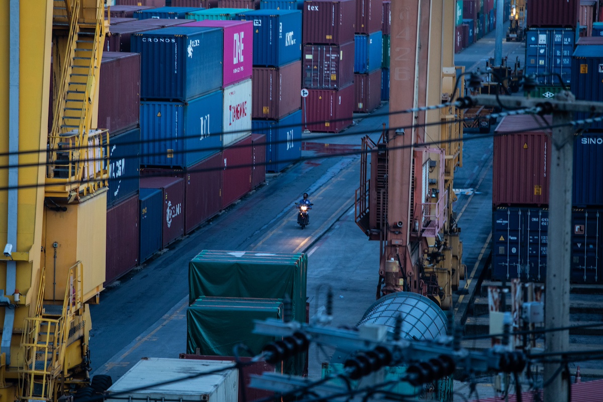 A motorcyclist rides past shipping containers stacked at the Bangkok Port. Photograph: Taylor Weidman/Bloomberg