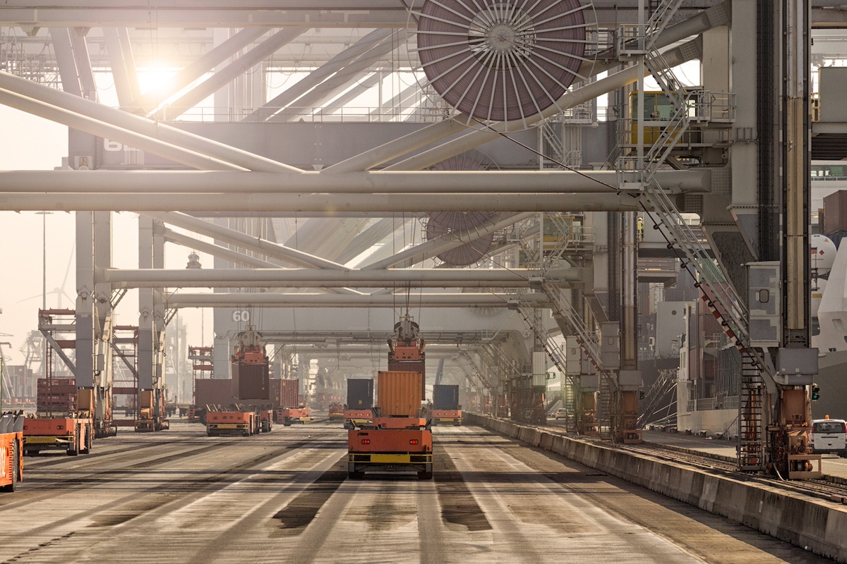 Automated Guided Vehicles moving shipping containers to and from gantry cranes in a port container terminal.