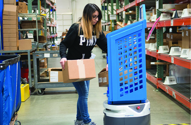 A warehouse worker puts items in a tote on an autonomous mobile robot (AMR). Photo by Lucas Systems.