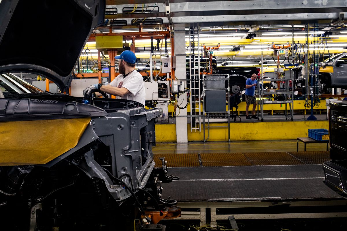 A worker installs an engine at a General Motors assembly plant. Photographer: Emily Elconin/Bloomberg