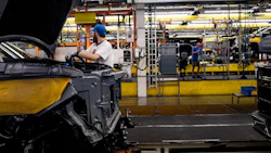 A worker installs an engine at a General Motors assembly plant. Photographer: Emily Elconin/Bloomberg