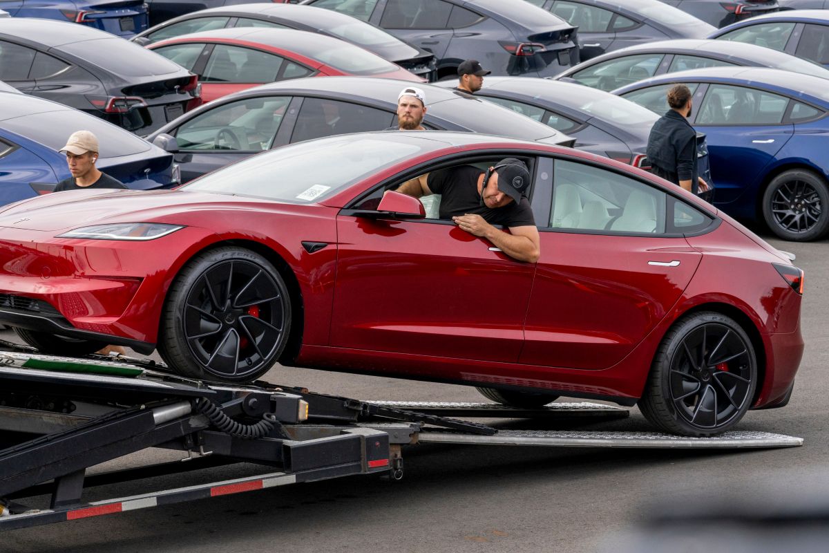 A worker unloads a Tesla Model 3 at a logistics drop zone in Seattle. Photographer: M. Scott Brauer/Bloomberg