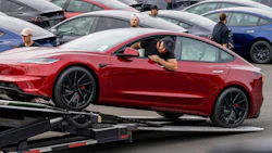 A worker unloads a Tesla Model 3 at a logistics drop zone in Seattle. Photographer: M. Scott Brauer/Bloomberg