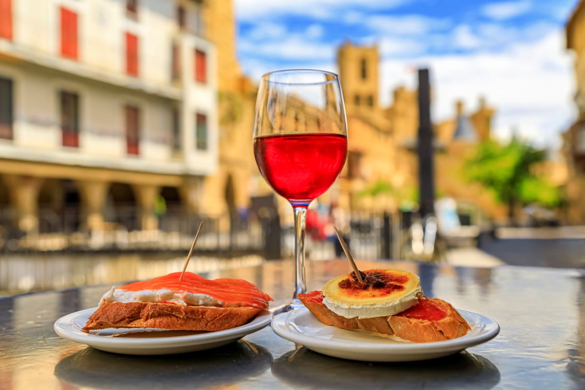 Tostadas with salmon and crab and baked cheese pintxos or tapas with a glass of Spanish rose wine outside a cafe in the medieval town of Olite, Spain. Photo: iStock/SvetlanaSF