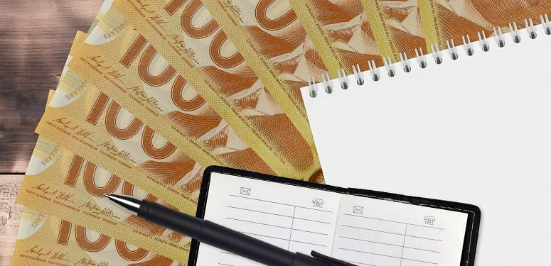 100 Canadian dollars bills fan and notepad with contact book and black pen. Concept of financial planning and business strategy