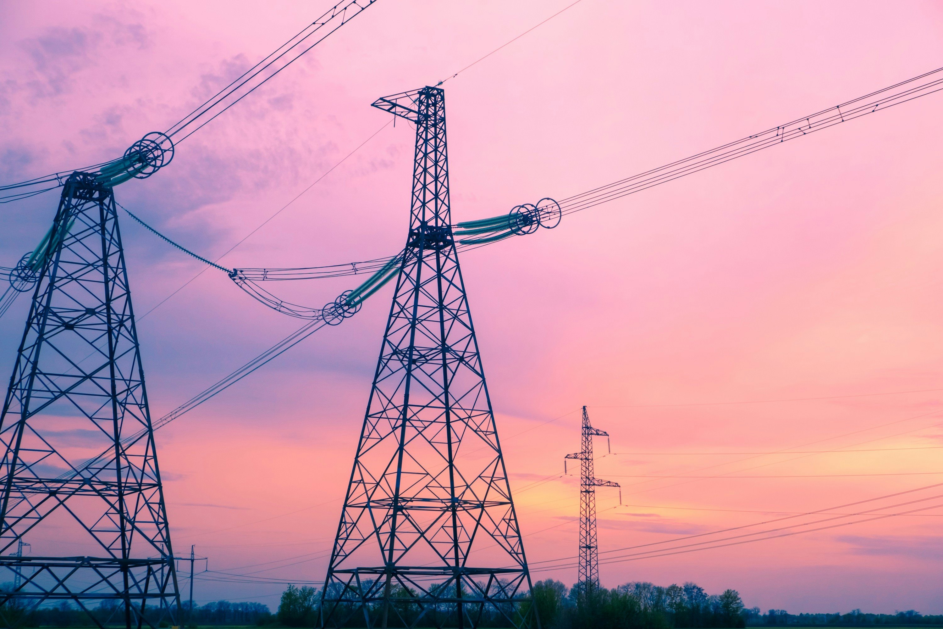 Two high-voltage electrical transmission towers. | Photo by Evgeniy Alyoshin