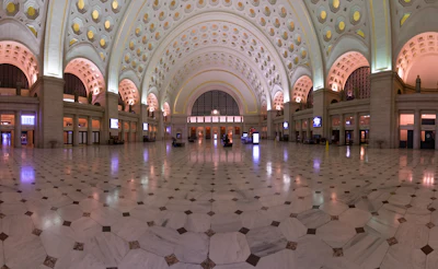 Grand interior hall of Union Station featuring ornate coffered ceiling with geometric patterns, illuminated arches, and symmetrical architectural design