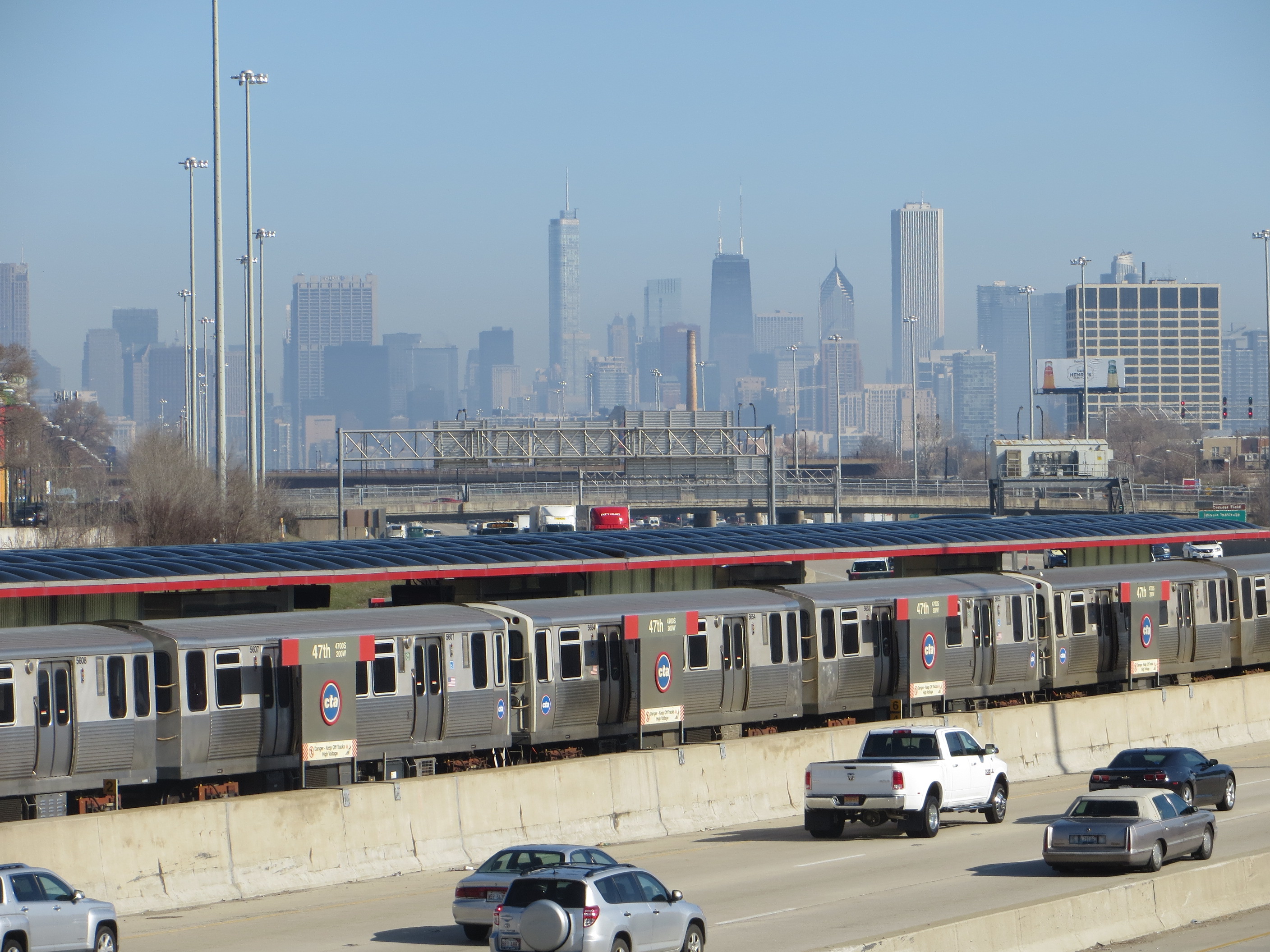 Chicago skyline with CTA trains parked along the waterfront and vehicles on a concrete platform below