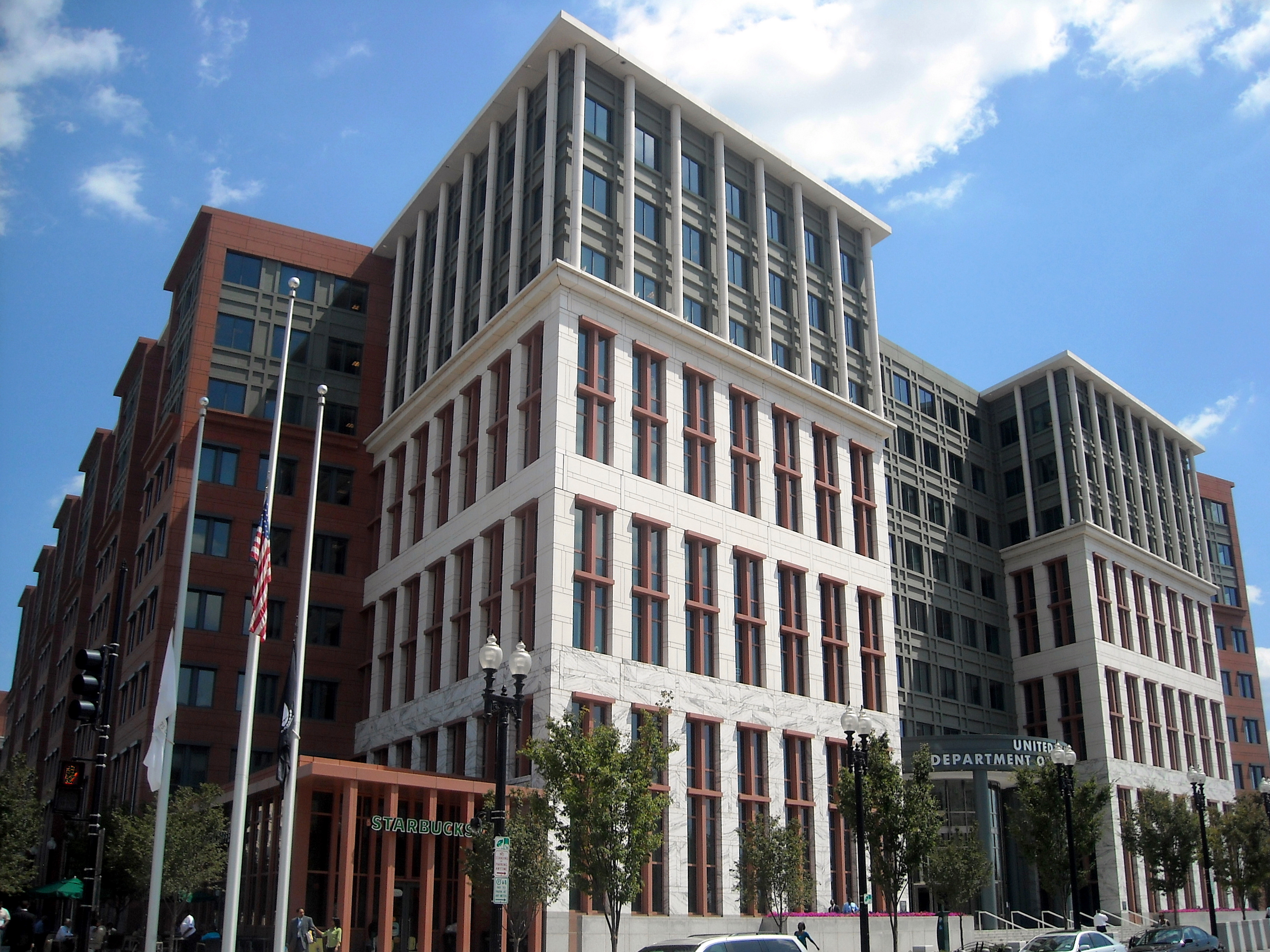 Modern and classical government office buildings on urban street with American flag and street-level signage