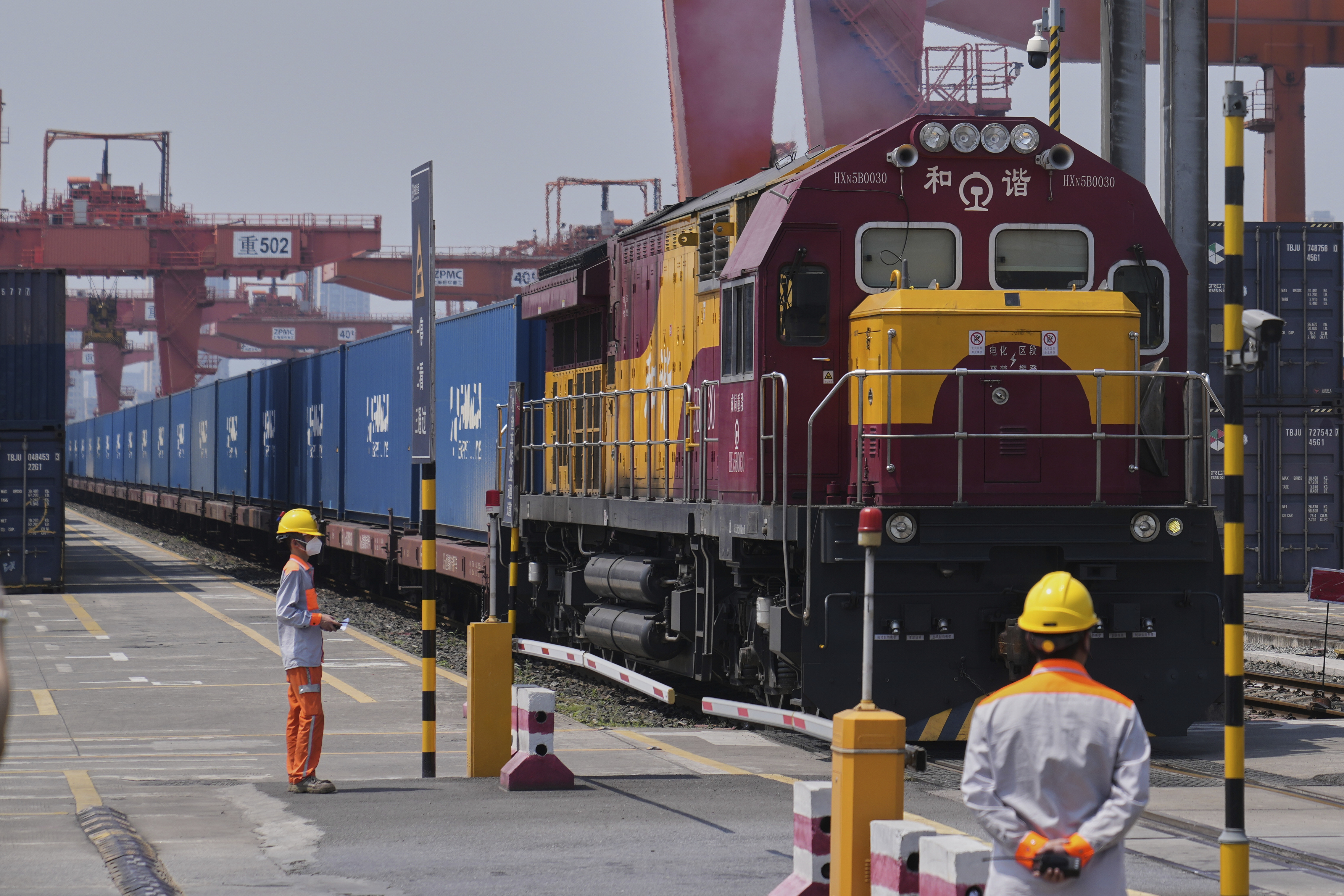 Workers watch as a train loaded with containers leave Chongqing Railway Container Terminal Station in southwest China's Chongqing Municipality on Tuesday, May 20, 2025.