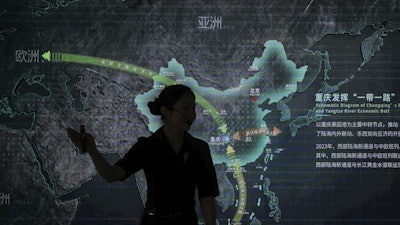 A worker walks by a display board showing the Chongqing Railway Hub for the One Belt One Road project, at the Chongqing Railway Container Terminal Station in southwest China's Chongqing Municipality on Tuesday, May 20, 2025.