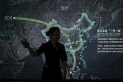 A worker walks by a display board showing the Chongqing Railway Hub for the One Belt One Road project, at the Chongqing Railway Container Terminal Station in southwest China's Chongqing Municipality on Tuesday, May 20, 2025.